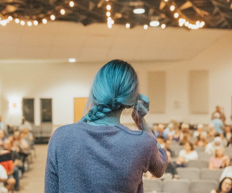 a woman with blue hair standing in front of an audience